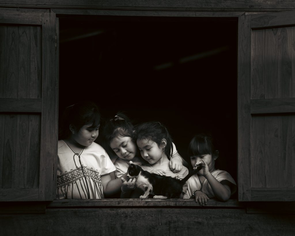 child holding a cat in a rural village, photographed by Atit Siri